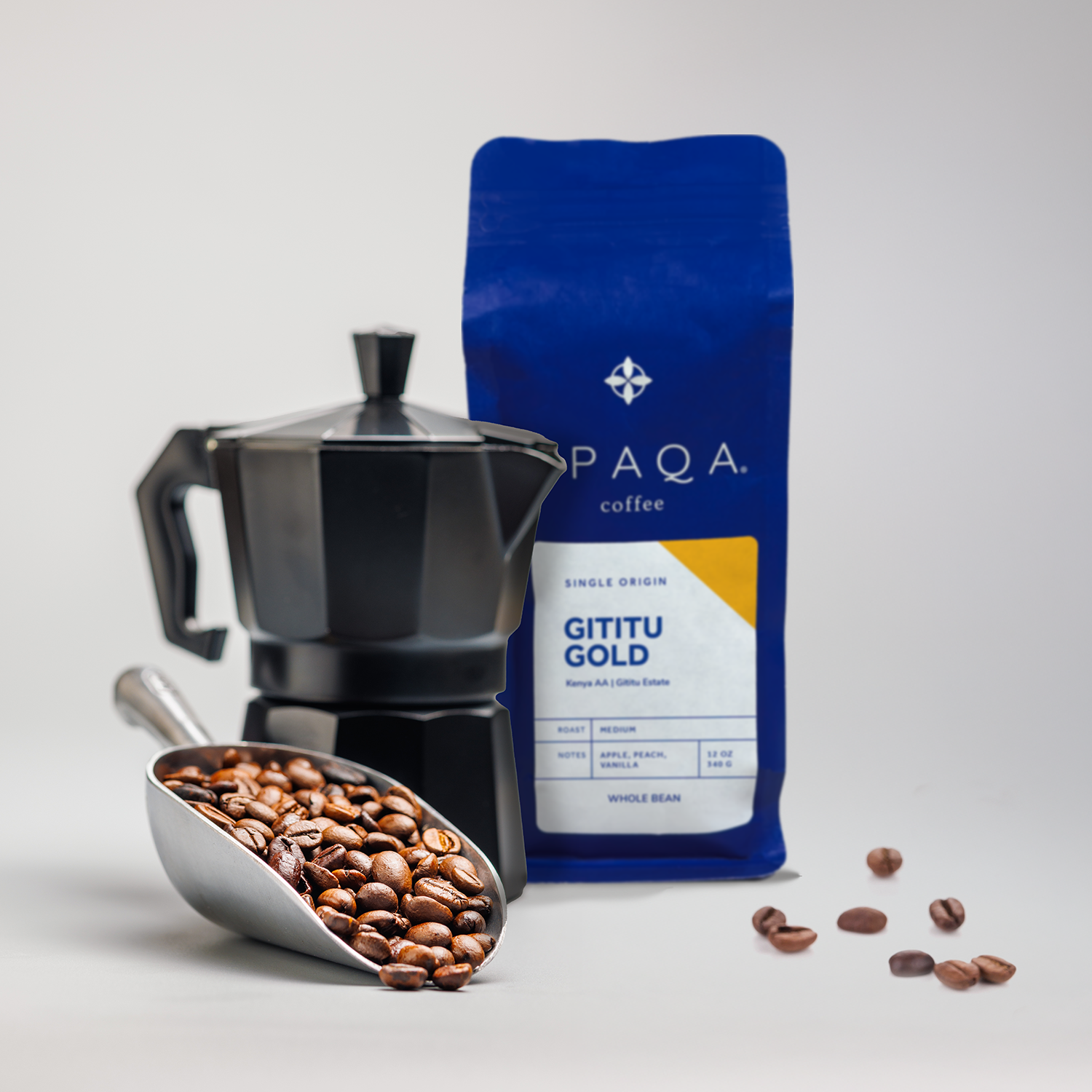 PAQA coffee bag, scoop of coffee beans, and espresso maker on a light gray background