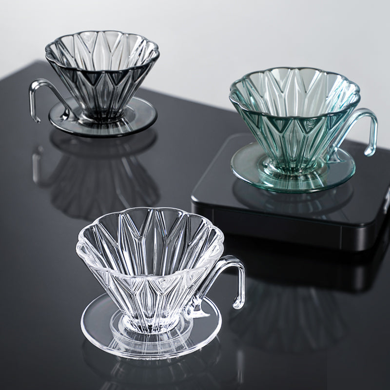 Three glass coffee filters on a reflective surface with a light gray background