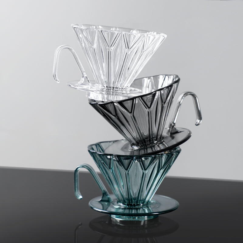 Set of three glass coffee filters stacked on a dark surface with a light gray background