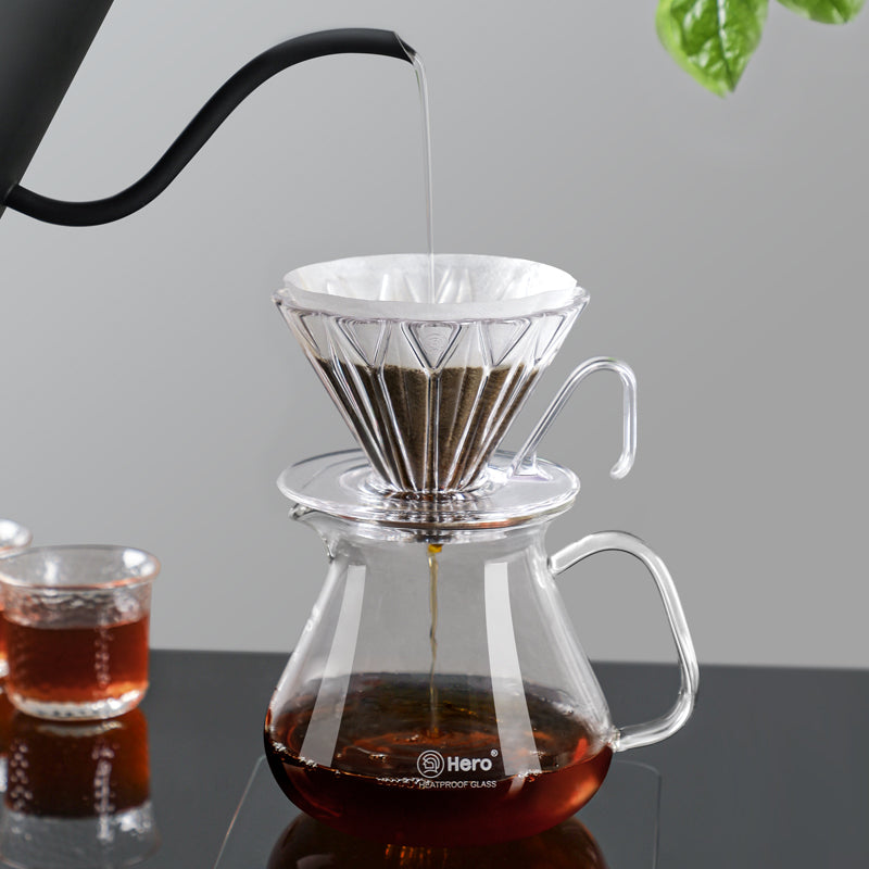 Coffee brewing process using a clear glass coffee maker with a white filter, Hero brand visible.