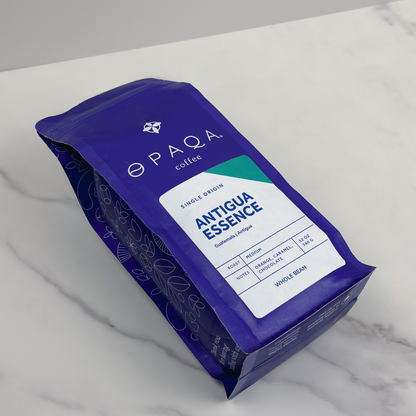 Opaqa Coffee's Antigua Essence bag on a marble surface, featuring notes of orange, caramel, and chocolate