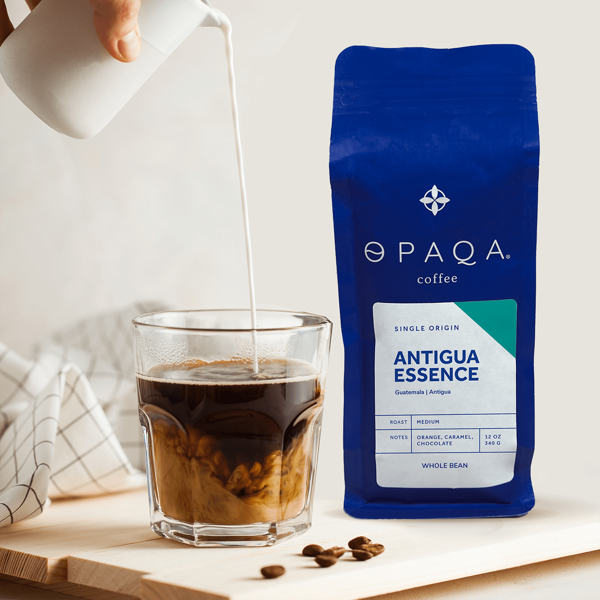 Antigua Essence coffee bag with a pour of cream into iced coffee, emphasizing its smooth, caramel notes