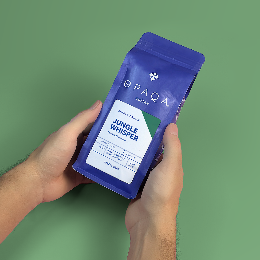 Hands holding the Jungle Whisper coffee bag, emphasizing its Sumatra origin and dark chocolate, cedar notes