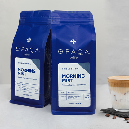 Two blue OPAQA coffee bags labeled 'Morning Mist' on a white background with a cup of coffee.