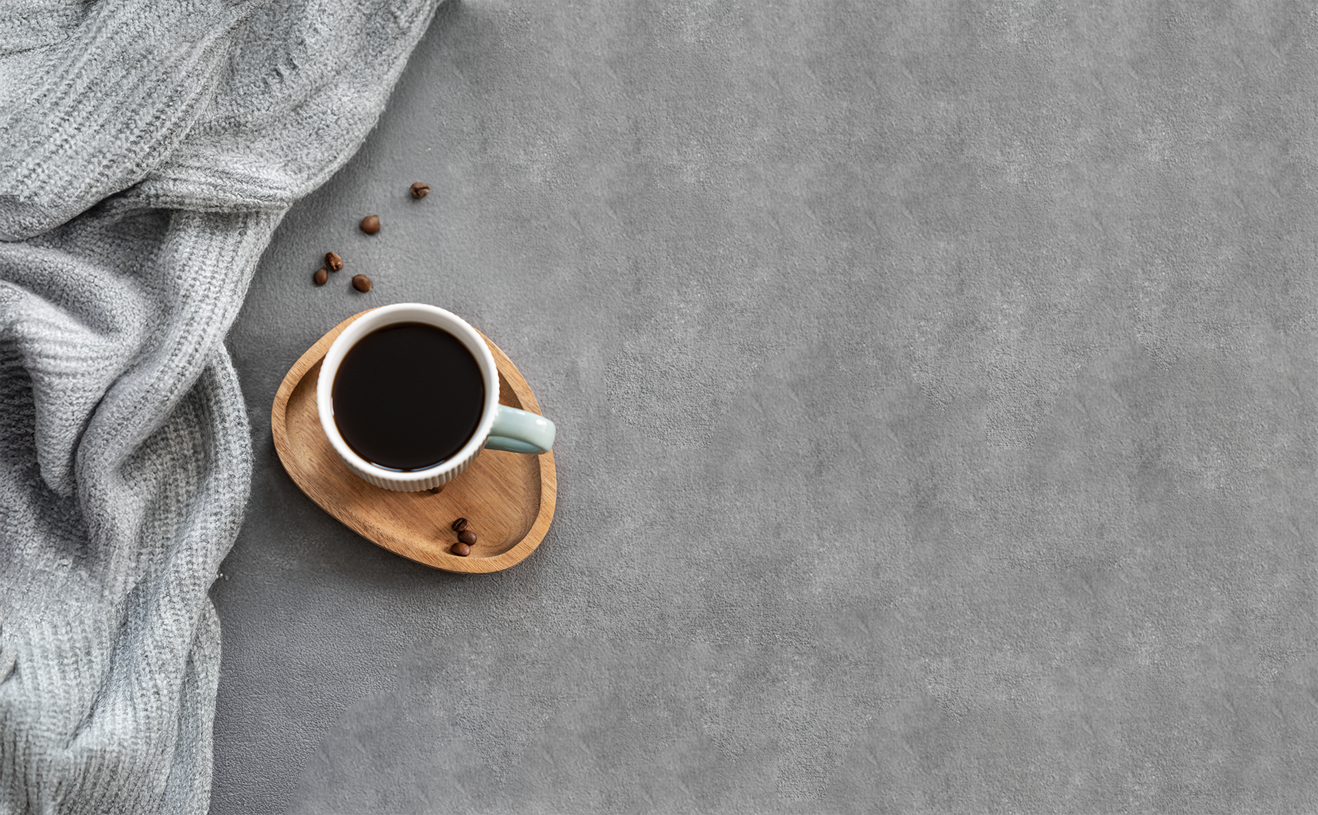 Cup of coffee on a wooden coaster with a gray textured background